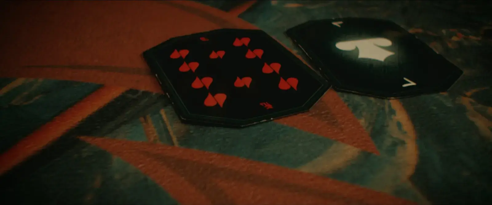 Two playing cards on a patterned carpet, one showing the eight of hearts and the other the ace of spades.