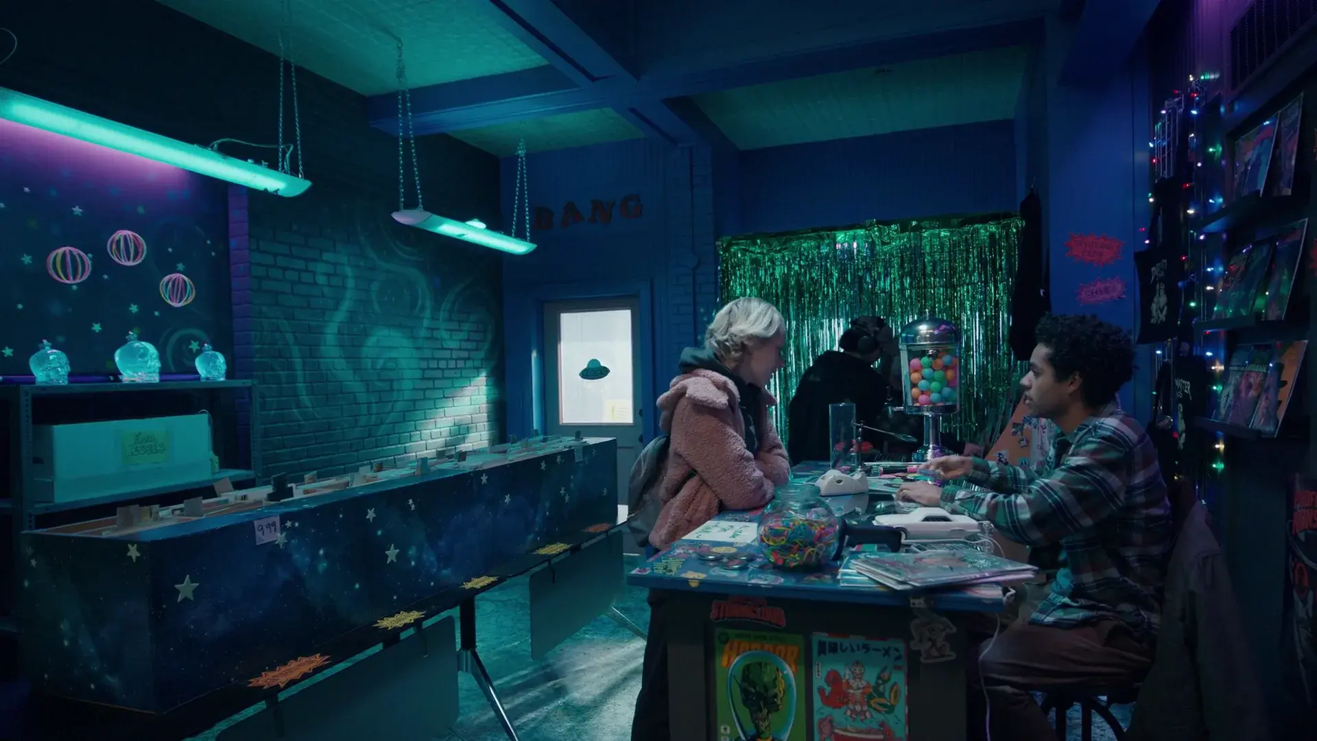 Wide view of the comic shop: candy jars, comic racks, tinsel curtain and illustrated walls