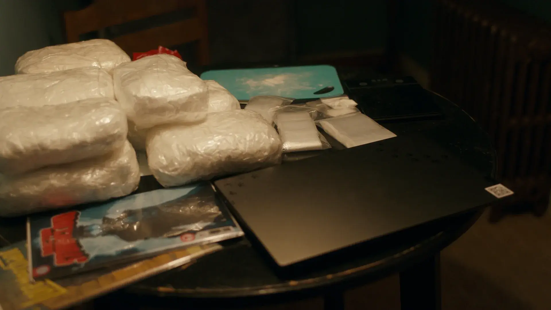 Wrapped packages and a comic book on a motel table next to a closed laptop