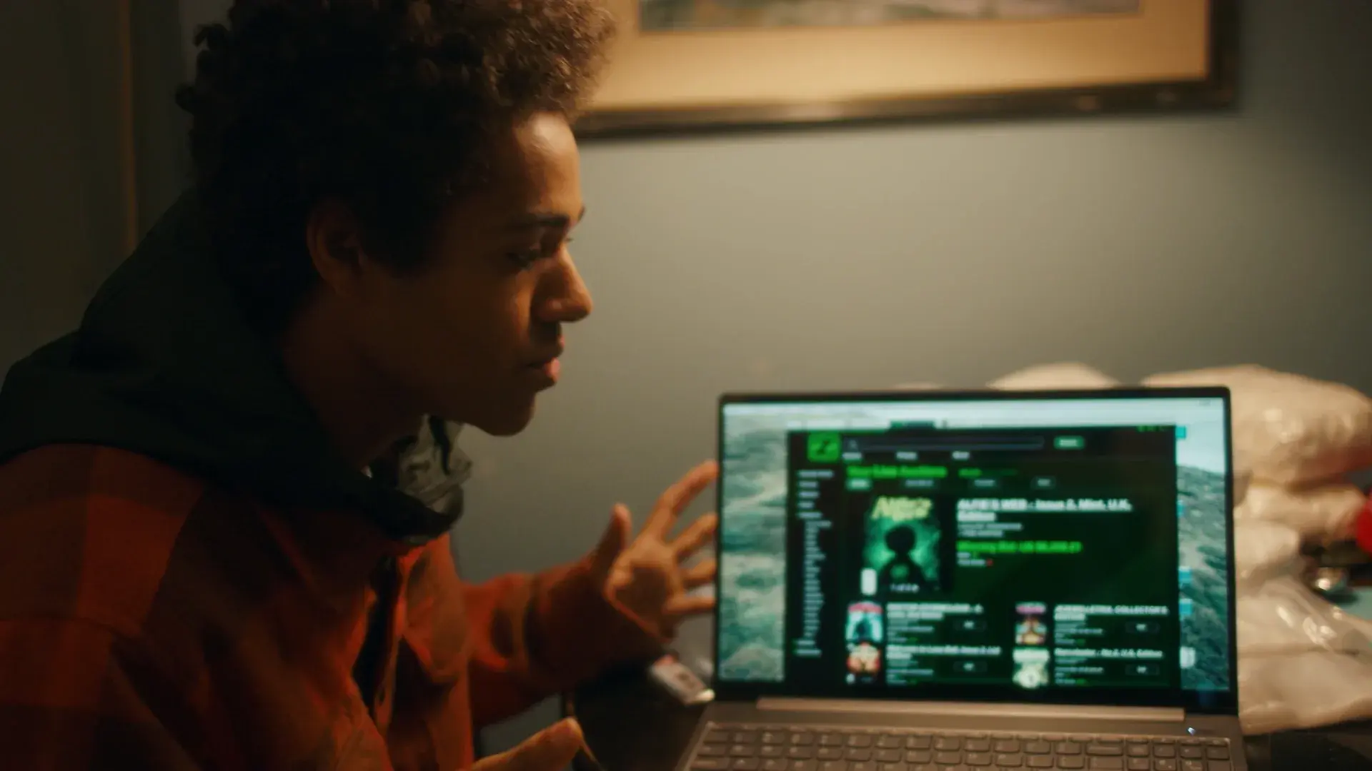 A young man gestures at a laptop showing the auction site graphic